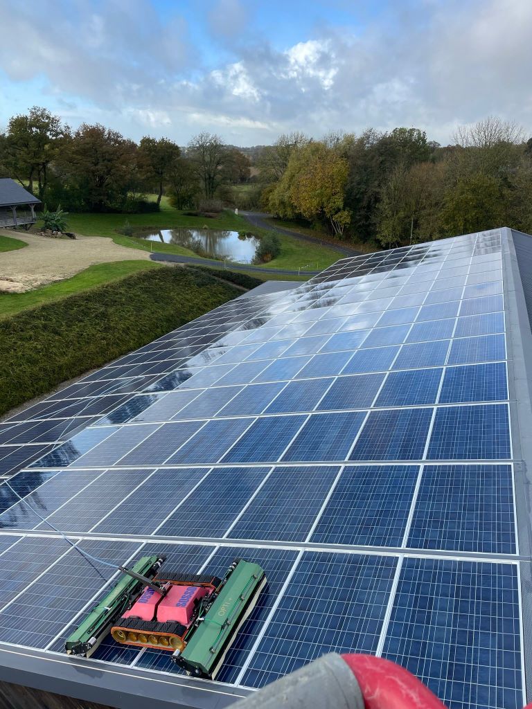 Sosso, notre robot en train de nettoyer des panneaux solaires sur le toit d'un bâtiment agricole